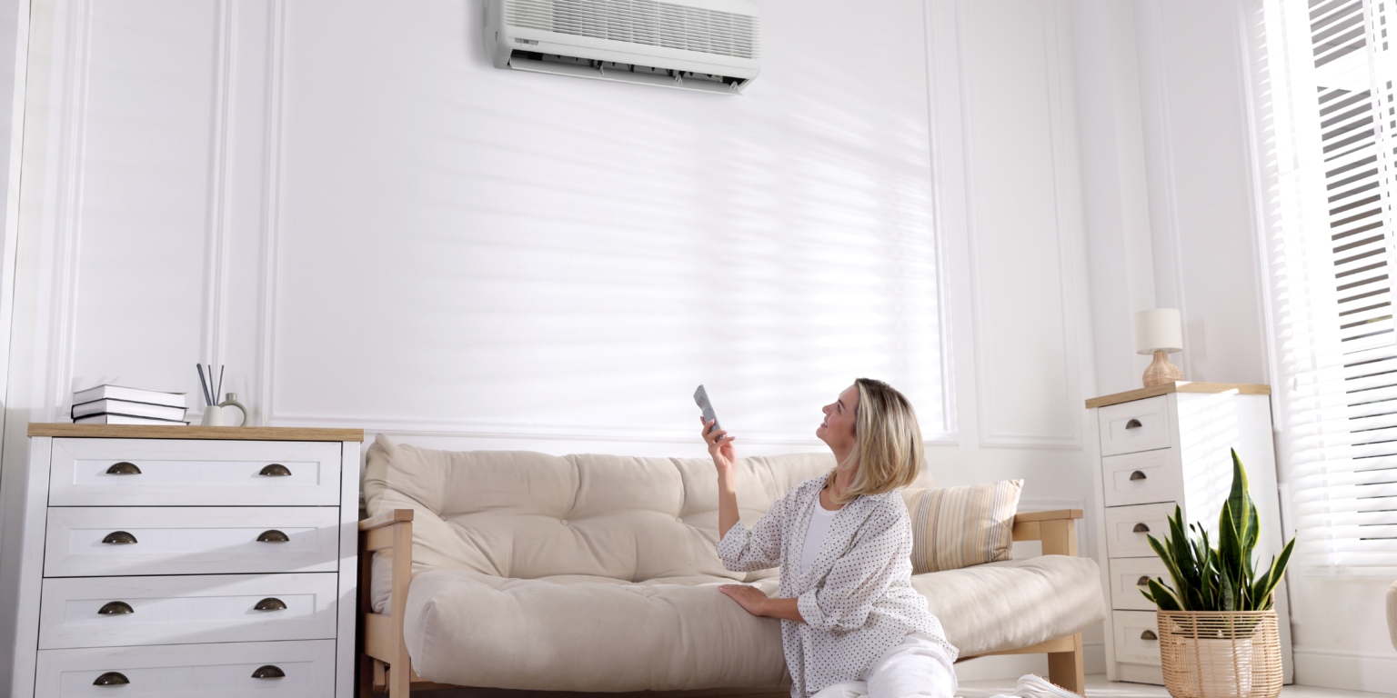 A lady controlling the indoor air conditioning unit in her home.